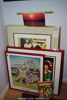 Overview of three framed prints stacked against wall with Beryl Cook New York book visible