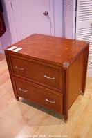 Front angled view of the two-drawer wooden filing cabinet with metal handles and silver corner protectors.