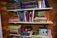 Shelves of books and audio programs including business and self-help books, sealed Blair Singer training sets, various titles, and a Schober sound-tuning machine.