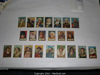 Full view of 22 tobacco cards arranged in three rows on a white surface, showing various historical figures from the 1911 and 1952 sets.