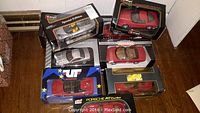 Photo showing nine die-cast sports cars in original boxes, including red and silver Ferraris, with various scales and brands visible.