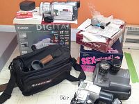 Overall view of lot showing Canon camcorder on its box, TeamRee camera bag holding lenses, adult massage kit and boxed adult games stacked.