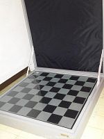Glass chessboard inside open aluminum case revealing clear and black 18×18 grid