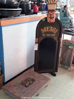 Tall Menu of the Day chalkboard sign with chef figure holding the black sign, showing the item standing upright.