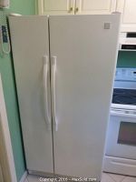 Closed front view of white Kenmore side-by-side refrigerator with vertical handles.
