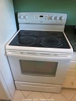 Front view of white Kenmore glass-top range installed between cabinets