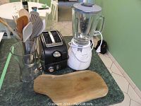 Sunbeam toaster, Beaumark blender, wooden utensils in glass vase, wooden cutting board on countertop