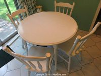 Top and side view of the white painted round kitchen table with four matching chairs around it, showing the wood finish and painted surface.