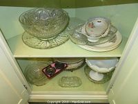 Top shelf with clear embossed glass bowls and assorted floral pattern and plain white dishes showing Wedgwood, Nippon, and Royal Tudorware pieces
