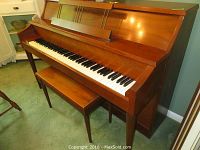 Forward view of walnut upright piano with closed lid and bench