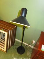 Full view of one black floor lamp with conical shade, showing height and base