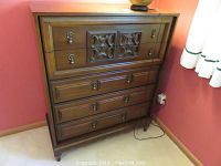 Front view of the wood dresser showing its five drawers, two central carved panels on top drawer, and the metal ring pull handles.