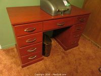 Front view of wood kneehole desk showing all drawers closed and metal pulls visible.