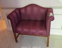 Front view of burgundy upholstered bench showing backrest, armrests with rolled design, and wooden legs.