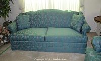 Front view of teal patterned Thomasville sofa with two accent pillows and arm covers.