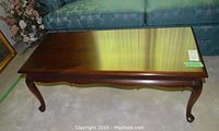 Top-down angle showing polished mahogany coffee table top with slight surface reflection and minor wear.