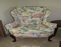 Front view of floral print wing chair with wood cabriole legs