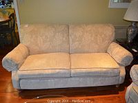 Front view of beige floral sofa showing two seat cushions and rolled arms