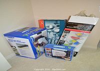 Four boxed items on floor: Dr. Scholl's massage mat, Nike yoga stretching kit, electric shampoo dispenser, and boxed shower and bath caddy.