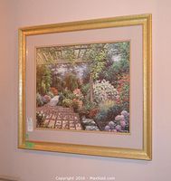 Framed print hanging on wall showing detailed garden pathway under pergola with various plants and flowers.