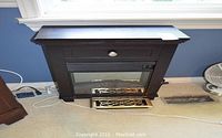 Full view of the compact electric fireplace showing dark wood finish and decorative metal grate inside glass front.