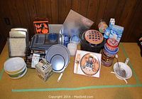 Overview photo showing all items on a table including Pyrex bowls, Wilton cake pans, canning pot, tins, Snowman cake plate with server, food mill, and Brita pitcher.