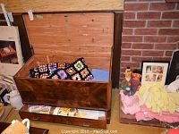 Full view of the heirloom cedar lined chest open showing the colorful crocheted blanket and blue textile inside along with linens in bottom drawer.
