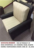 Front-side view of black synthetic wicker patio chair with beige striped cushions on carpeted showroom floor