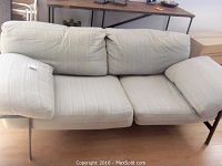 Front view of the B and B Italia Diesis couch with beige striped cushions and black metal frame.