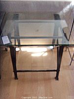 Top and side angled view of Pottery Barn glass top side table with black cast iron frame showing the glass surface and structural details.