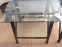 Side angle view showing the cast iron legs and structure supporting the glass top on wooden floor