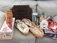 Full lot on couch showing cordless vacuum box, butcher block, baskets with utensils, fabric apron, sign and other kitchen accessories.