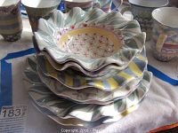 Stack of seven fluted McKenzie-Childs stoneware plates/bowls with multicolor patterns