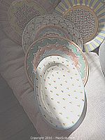 Six round charger plates and one oval tray fanned out on a couch