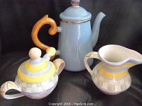 Full set arranged showing blue coffee pot, sugar bowl with lid and spoon, and cream pitcher, all on black background.
