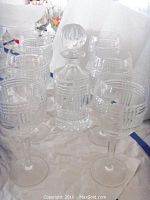 One decanter with six wine glasses displayed on white surface