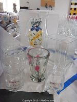 Group photo of multiple glass items including Orient and Flume rose bud vase, clear vases and Hennessy glasses displayed on a white surface.