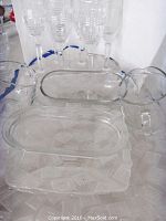 Six stemmed flutes arranged at rear with two small glass creamers and two clear glass oval serving trays at front