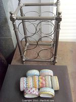 White metal wine rack with 6 circular holders, octagonal frame and round reeded ribs, 16 inches tall.