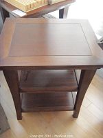 Front view of cherry finish end table showing two lower shelves and tapered legs.