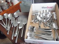 Various spoons and forks displayed on table and in box