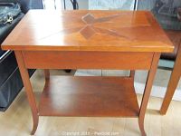 View of the side table front showing drawer, bottom shelf, and curved legs.