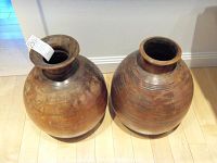 Pair of bulbous earthenware urns placed on a wooden floor, showing overall shape and finish.