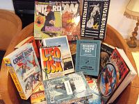 Shows the variety and condition of the comic book price guides and additional books placed on a wooden chair.