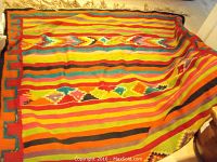 Full view of colorful woven geometric Aztec design rug laid out on the floor showing horizontal stripes and diamond pattern details.