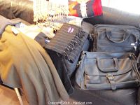 Wide view of the lot showing several scarves and two laptop bags on a couch: black Coach leather laptop bag with shoulder strap and a black Tumi laptop bag, along with various scarves.