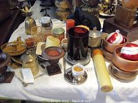 Photo of assorted candles and candleholders on a table including pillar candles, votive candles, metal and glass holders, and two striped red and white candles in wooden holders.