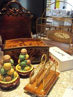 Wide view of miscellaneous lot items showing two colorful fruit or nut cluster figurines on wooden bases, a wooden hinged box, metal magazine rack, and domino set box.