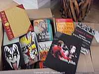Books spread in box showing a mix of hardcovers and paperbacks including Elton John and Feng Shui titles