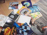Over 20 assorted rock and pop vinyl LP album covers arranged on floor.